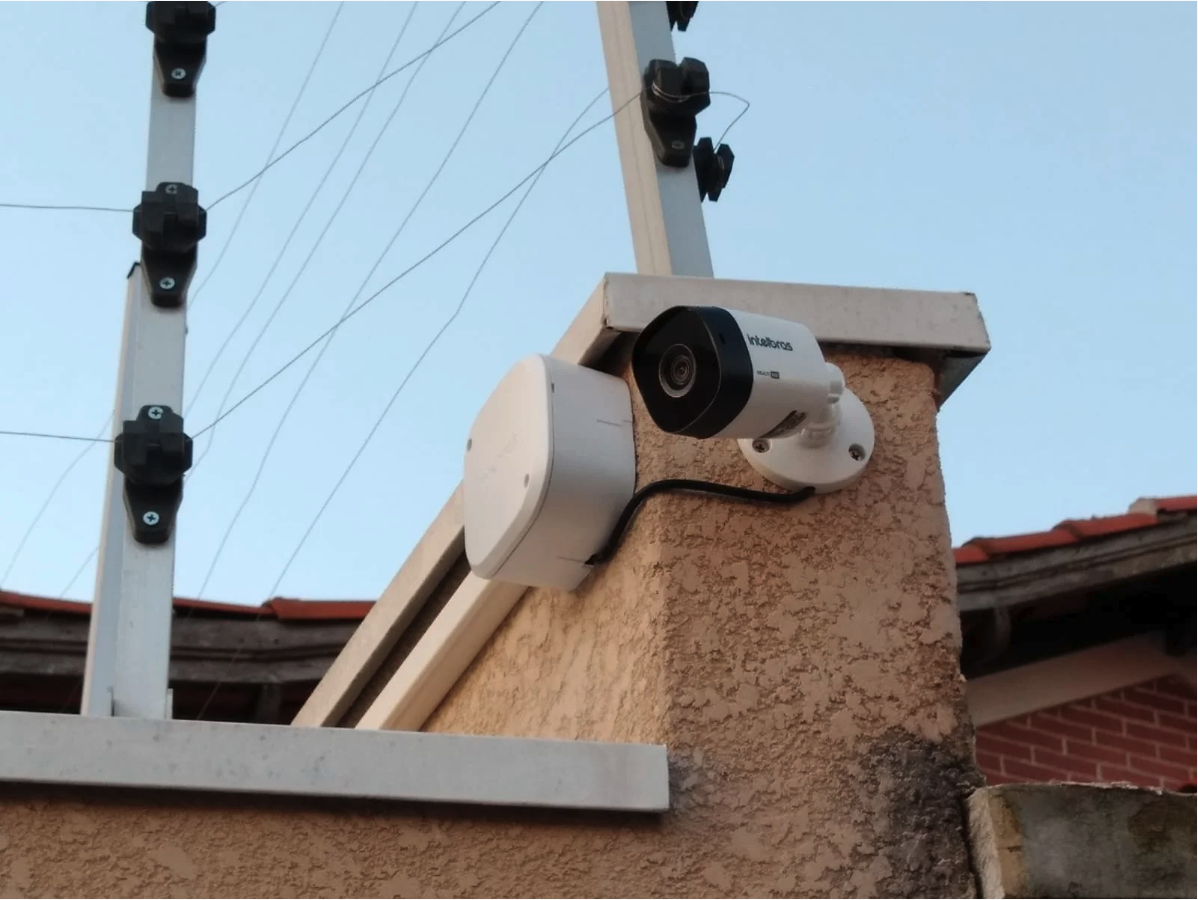 Câmera de segurança Intelbras instalada junto a cerca elétrica em residência